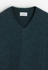 Suéter de pico verde oscuro hecho de un suave tejido de punto. Cuenta con un cuello acanalado y un pequeño logo bordado en el lado izquierdo del pecho. Tamaño XL.