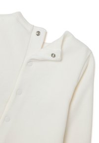 Suéter de algodón blanco con un escote redondeado, cierre a presión en el cuello y una textura suave, con un diseño simple y minimalista.