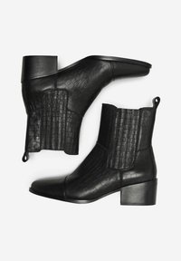Botines negros con un patrón texturizado de cocodrilo, paneles laterales elásticos, punta afilada y un tacón bajo en bloque.