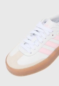 Hvide lædersneakers med pink striber, ruskind toe cap og gummisål. Har hvide snørebånd og en polstret krave for støtte.