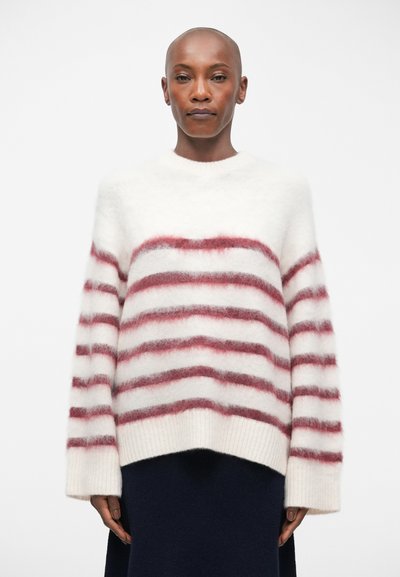 Pull rayé blanc et bordeaux. Texture douce et moelleuse avec un col rond et des manches larges. Ourlet avec finition côtelée.