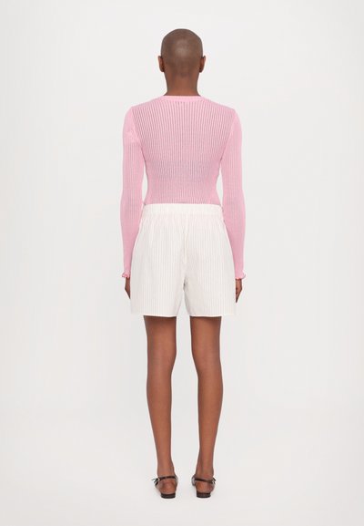 Rosa stripete langermet topp kombinert med hvite stripete shorts; glatt stofftekstur, elastisk midje og flate sandaler.