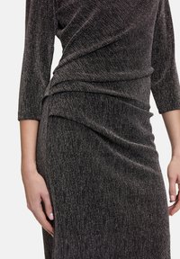 Vestito metallico nero con maniche a tre quarti, caratterizzato da un design drappeggiato e un tessuto testurizzato. Notevole lucentezza e sottili righe verticali.