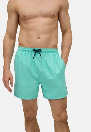 Bañadores turquesa hechos de una tela suave y ligera. Cuenta con una cintura con cordón, bolsillos laterales y un corte relajado.