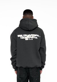 Dunkelgrauer Hoodie mit einem großen, stilisierten weißen Grafiktext auf dem Rücken. Verfügt über eine Kängurutasche und eine Kordelzugkapuze.