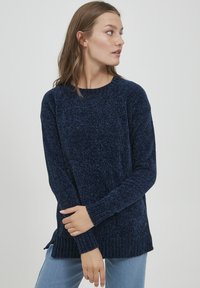 Pulover tricotat de culoare bleumarin, cu finisaj texturat, decolteu rotund și tiv cu nervuri. Are fante laterale și mâneci lungi ajustate.