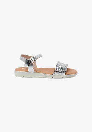 Silver metallic sandals with a woven strap, ankle buckle closure, and a light-colored sole. Smooth texture with a minimalist design.