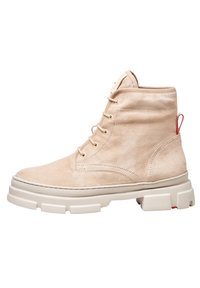 Botas de tobillo de ante beige con una suela blanca gruesa, que presentan ojales dorados, una tira roja para tirar y acentos laterales texturizados.