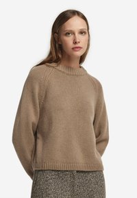 Beiger, grobstrick Pullover mit einem gerippten Hals- und Ärmelbündchen, der einen lässigen Schnitt und Raglanärmel aufweist. Ideal zum Layering.