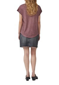 T-shirt à manches courtes de couleur bordeaux associé à une jupe en jean noire avec des bords effilochés. La tenue est complétée par des sandales à talons noires.