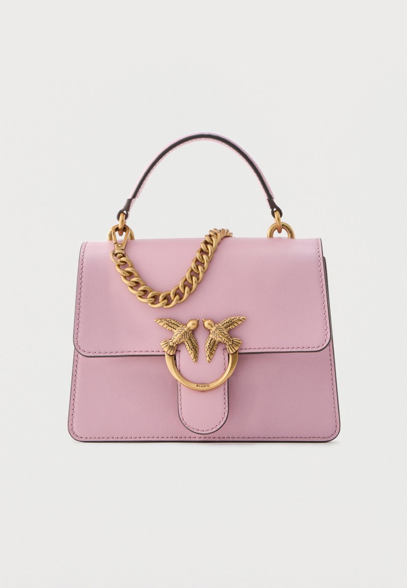 Ροζ δερμάτινη τσάντα χειρός με χρυσό κούμπωμα σε σχήμα πουλιού και αντίστοιχη χρυσή αλυσίδα, με πάνω λαβή, σε λευκό φόντο.