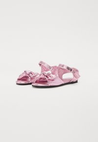 Rosa metalliska sandaler med knutdesign fram, öppen häl och justerbar rem. Platt sula med slät textur och lätt konstruktion.