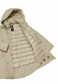 Beige buitenjack met een gewatteerde binnenvoering, voorzien van een capuchon, ritsluiting en drukknoopsluiting. Inclusief verzorgings- en stoficonen.