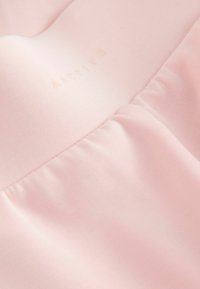 Tissu rose doux avec un léger froncement et le mot « ACTIVE » embossé légèrement sur la partie supérieure du matériau.