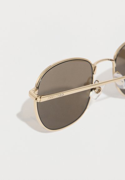 Γυαλιά ηλίου με χρυσή κορνίζα και σκοτεινούς ορθογώνιους φακούς με τη χάραξη "JIMMY CHOO" στο λεπτό πλαϊνό βραχίονα.