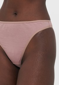 Gaismas mauve krāsa biksītes, izgatavotas no mīksta kokvilnas materiāla, ar gludu apdari, kontrastējošu beigu jostu un bezšuvju malām.