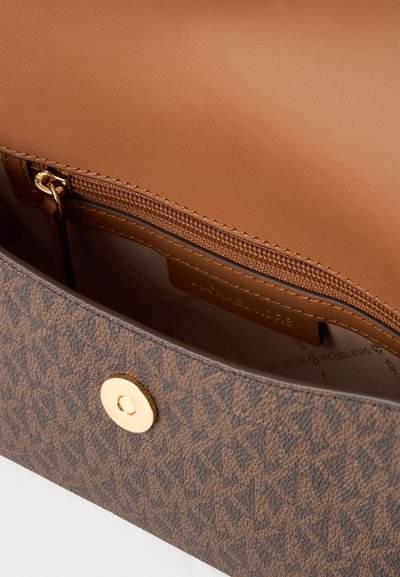 Крупен план на отворена кафява дамска чанта Michael Kors с видими джоб с цип, подплата с шарка, закопчалка в златист цвят и външна част с логото.
