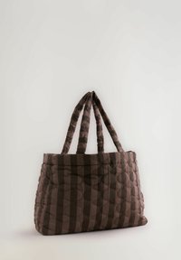 Braune gestepte Handtasche mit zwei gepolsterten Griffen und einem gestreiften Muster, die auf einer schlichten weißen Oberfläche aufrecht steht.