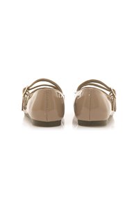 Bailarinas beige brillantes con punta redondeada, dos tiras delgadas y acentos de lazo en la parte trasera. Suela texturizada para agarre, diseño minimalista.