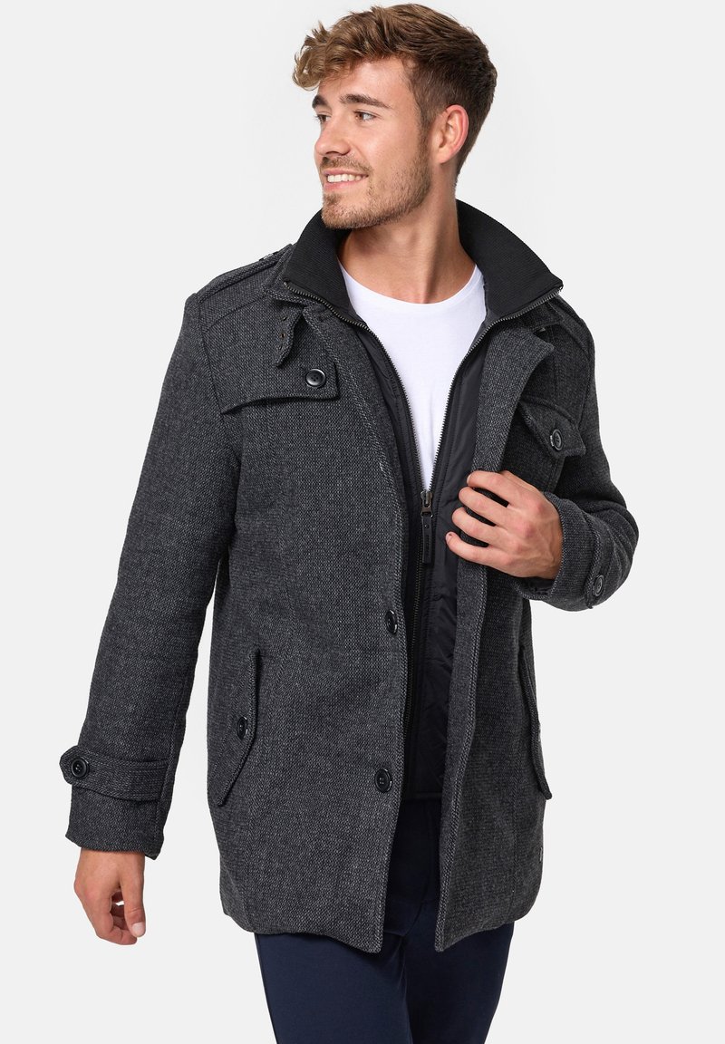 Mörkgrå kappa för män med texturerad tyg, knäppningar, fickor med klaff och en kontrasterande innerfoder; har en hög kragdesign.