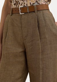 Pantalon en vichy marron avec plis, accompagné d'une ceinture marron lisse avec une boucle rectangulaire en argent.