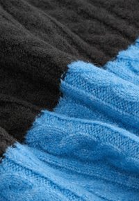 Gebreide stof in zwart en blauwe tinten, met een textuurpatroon en een zachte, pluizige textuur, met een naadloze mengeling van kleuren.