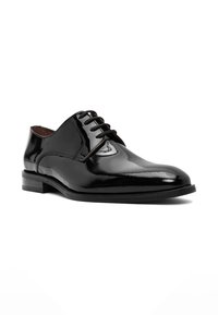 Chaussure habillée en cuir noir au fini brillant, à bout rond, avec six œillets pour les lacets, un talon bas empilé et des coutures minimales.
