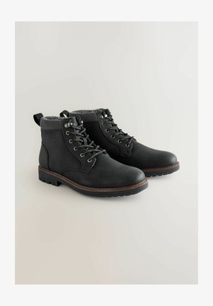 Mustad mustsa nahast ankle boots, millel on tekstuuriga kudumine kaelus, vastupidav nööpimisdisain ja kummitald, mis tagab haarde.