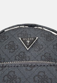 Svart texturerad handväska med en framträdande triangular metall-logotyp och silverfärgade detaljer. Designen inkluderar ett subtilt mönster och dragkedjestängning.