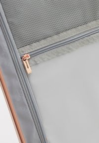 Pochette grise avec une section en maille texturée, fermeture éclair argentée et quincaillerie en or rose. Surface intérieure lisse avec un branding subtil.