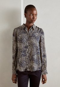 Navy button-up shirt with a scattered cream dot pattern, long sleeves, pointed collar, and a soft, smooth fabric texture.