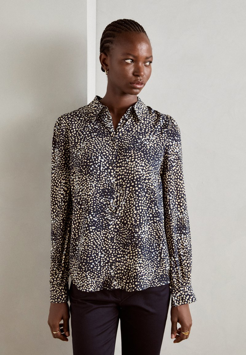 Navy button-up shirt with a scattered cream dot pattern, long sleeves, pointed collar, and a soft, smooth fabric texture.