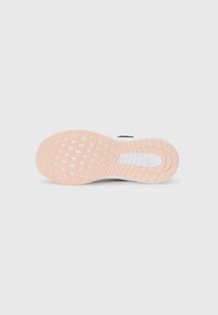 Semelle d'une sneaker, présentant une surface en caoutchouc texturée en pêche avec des motifs circulaires, entourée d'un intermédiaire blanc et d'un accent noir.