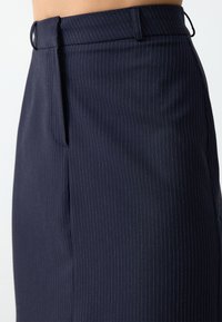 Marineblauwe op maat gemaakte broek met een streepjespatroon, voorzien van een platte voorkant, zijzakken en een gladde, textuurstof.