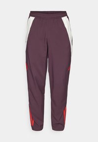 Bordeauxkleurige trainingsbroek met witte zijpanelen en rode accenten. Elastische tailleband, taps toelopende benen en rode logo-detail op de linker bovenbeen.