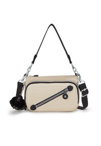 Beżowa torba z materiału z czarnym zamkiem błyskawicznym, srebrnymi elementami, odpinanym łańcuszkowym paskiem oraz czarnym pomponem przyczepionym do zamka.