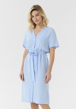 Vaaleansininen, lyhythihainen mekko, jossa on V-pääntie ja nappilukko. Mekossa on vyötäröhihna ja sileä kangas, joka istuu rentosti.