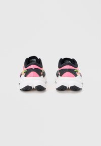 Coppia di scarpe sportive rosa, nere e gialle viste da dietro con suole bianche e suole esterne nere texturizzate su uno sfondo semplice.