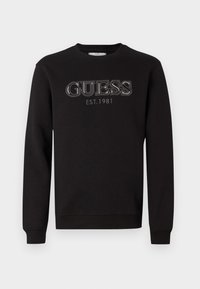 Fekete kerek nyakú pulóver hosszú ujjakkal, amelyen a mellkason kontrasztos cérnával hímezve található a "GUESS EST. 1981" felirat.