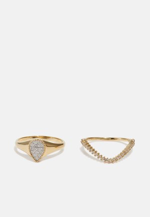 Gold rings set: left features a pear-shaped accent with clear stones; right is a V-shape design with small clear gems along the band.