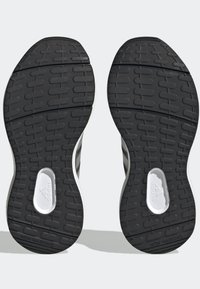 Suelas de goma negra con un dibujo en relieve. Presenta un inserto blanco con el logo "adidas". Diseño que no deja marcas.