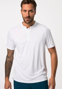 Polo shirt bianco a maniche corte con colletto leggero, abbottonatura a due bottoni e logo discreto sul petto. Texture liscia, vestibilità atletica.