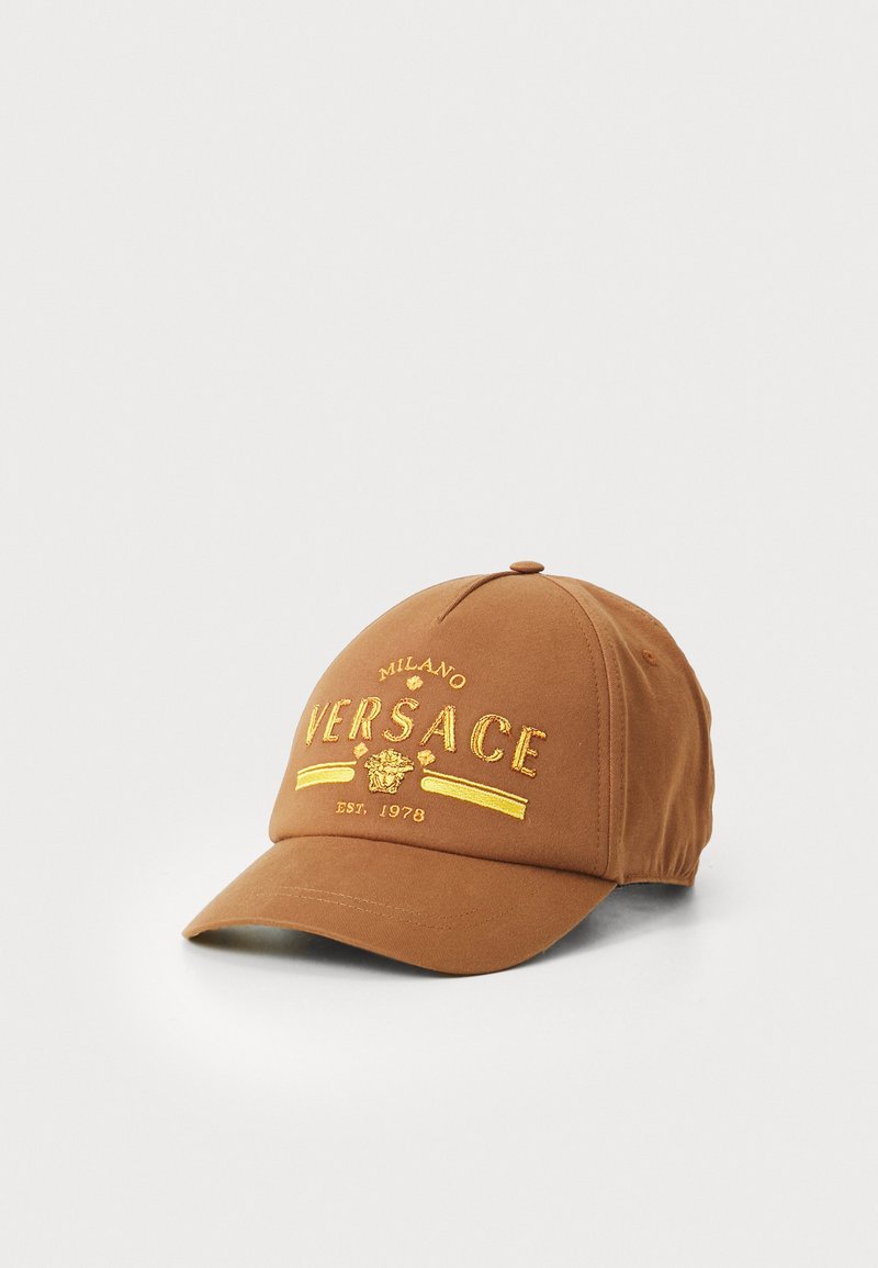 Brūns kokvilnas beisbola cepure ar zeltītu izšuvumu "VERSACE," dekoratīvām akcentiem un strukturētu malu.