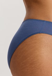 Blå bomullsblandning bikiniunderdel med en slät textur, medelhög design och elastisk midja med kontrasterande sömmar.