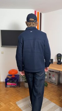 Veste bleu marine au design structuré, avec poches avant et un logo discret. Associée à un jean en denim foncé et une casquette.