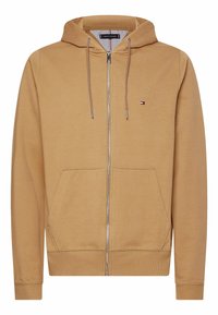 Tan zip-up hoodie gemaakt van gladde stof. Voorzien van een capuchon, voorzakken, ribgebreide manchetten en een klein logo-opdruk op de borst.