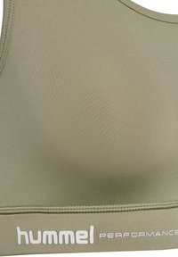 Sportowy stanik w kolorze oliwkowej zieleni wykonany z gładkiego, elastycznego materiału. Posiada szeroką, białą taśmę z logo oraz bezszwową konstrukcję zapewniającą komfort i wsparcie.