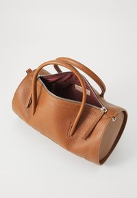 Brown pebbled leather handbag with rounded shape and two top handles. Zipped closure reveals maroon interior and a small brand label inside.
