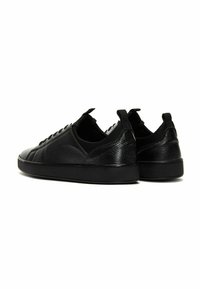 Sneaker in pelle nera con una finitura testurizzata, suola piatta in gomma, accenti lisci a contrasto e lacci che passano attraverso gli occhielli sulla parte superiore.