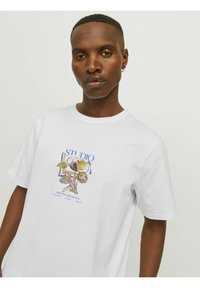 Hvid bomulds t-shirt med et farverigt trykt design, der har blomster-elementer og tekst, rund halsudskæring og korte ærmer.